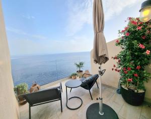 einen Balkon mit einem Tisch, Stühlen und einem Sonnenschirm in der Unterkunft Mare è rocca in Bonifacio