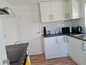 a kitchen with white cabinets and a sink and a microwave at The Albemarle in Hull