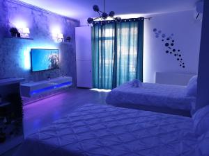 1 Schlafzimmer mit 2 Betten, einem TV und lila Beleuchtung in der Unterkunft Delux Studio Mamaia Nord in Năvodari