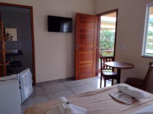 a bedroom with a bed and a table and a television at Pousada dos Pássaros in Quartéis