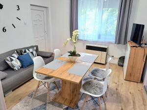 a living room with a wooden table and white chairs at Belvárosi Lux Apartman in Vásárosnamény