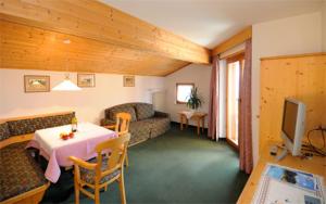 a living room with a couch and a table and a television at Pension Laurin in Schenna