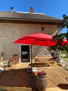 um deque de madeira com um guarda-chuva vermelho e um banco em L'instant présent em Echallon