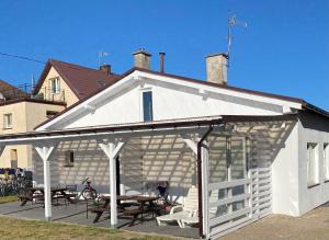 a white pavilion with a picnic table and tables at Domki i POKOJE PLAŻOWE in Darlowko