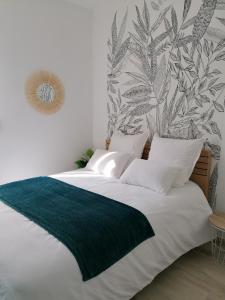 a bedroom with a large bed with a green blanket at Le manut, charme et confort in Dijon