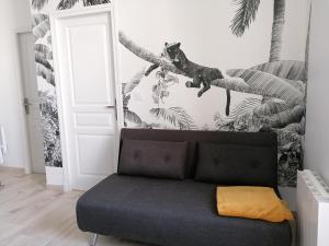 a living room with a couch and a dinosaur on a wall at Le manut, charme et confort in Dijon