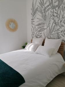 a white bed with white pillows and a wall mural at Le manut, charme et confort in Dijon