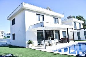 una casa blanca con una piscina frente a ella en Villa Can SeQuet (Playa de Muro), en Muro