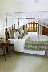 a bedroom with a white bed with a canopy at Tembo Court Apartments in Malindi