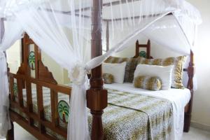 a bedroom with a canopy bed with white curtains at Tembo Court Apartments in Malindi
