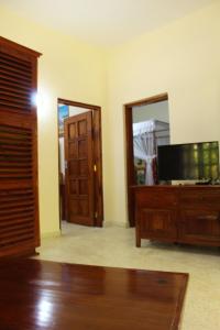 a living room with a tv and a wooden dresser at Tembo Court Apartments in Malindi