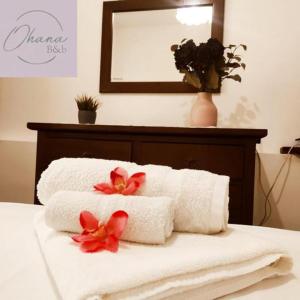 a couple of towels on a bed with flowers on it at Ohana B&B in Marina di Camerota