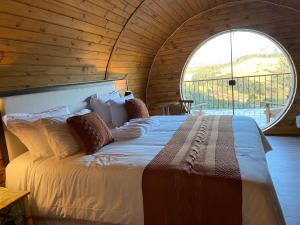 a bedroom with a large bed with a large window at Pousada Villa Barril in Monte Verde