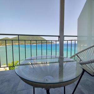 a glass table on a balcony with a view of the ocean at Ponti Bay Apartments in Vasiliki