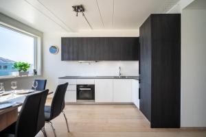 kuchnia z białymi szafkami oraz stołem i krzesłami w obiekcie Arctic Homes - Premium Tromsø Residence w mieście Tromsø