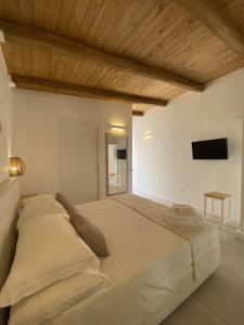 a large bed in a white room with a flat screen tv at Koralline accommodation in Tropea