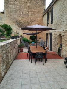 een houten tafel met een parasol op een patio bij L'auberge mondevillaise in Mondeville