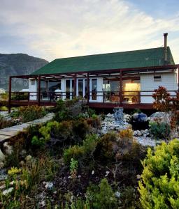 a house with a green roof in a garden at Brandys beach house bettys bay in Bettyʼs Bay