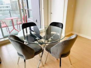 a glass table with four chairs around it in a room at Lovely downtown 2 bedroom condo with free parking in Victoria