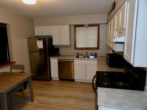 uma cozinha com armários brancos e um frigorífico de aço inoxidável em The Washburn Inn em Washburn