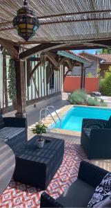 een achtertuin met een zwembad en een houten pergola bij La Chantourelle 