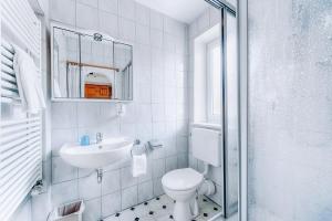 a white bathroom with a toilet and a sink at Hotel Nuss in Grainau