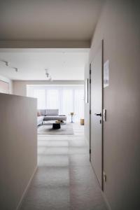 a hallway leading to a living room with a couch at - Carijoca - Gemoderniseerd, lichtrijk & zijdelings zeezicht app in Koksijde