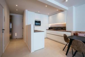 a kitchen with white cabinets and a table and chairs at - Carijoca - Gemoderniseerd, lichtrijk & zijdelings zeezicht app in Koksijde
