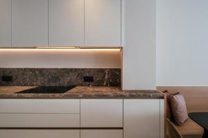 a kitchen with white cabinets and a marble counter top at - Carijoca - Gemoderniseerd, lichtrijk & zijdelings zeezicht app in Koksijde