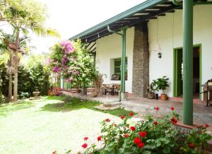 a house with red flowers in the yard at La Liebre bed and breakfast in El Retiro