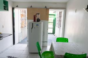 uma cozinha com uma mesa, cadeiras verdes e um frigorífico em FLAT ACONCHEGANTE em Teresina