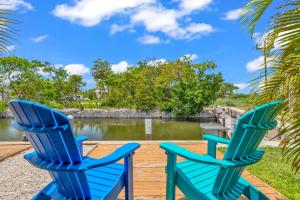two blue chairs sitting on a deck next to a body of water at Coconut Cay Resort in Marathon