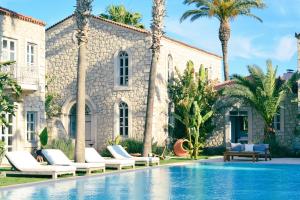 a villa with a swimming pool and palm trees at Manastir Alacati Hotel in Alaçatı
