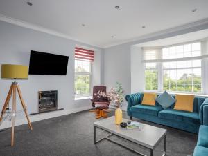 uma sala de estar com um sofá azul e uma televisão em Llety Ednyfed em Criccieth