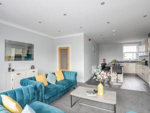 uma sala de estar com dois sofás azuis e uma mesa em Llety Ednyfed em Criccieth