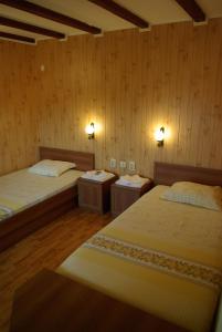 two beds in a room with wooden walls at Guest House Dan Kolov in Syennik