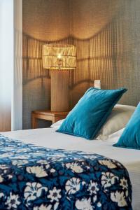 a bedroom with a bed with blue pillows and a lamp at La Cremaillere Hôtel-Restaurant in Courseulles-sur-Mer