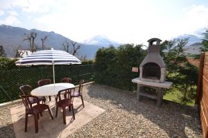 a table with an umbrella and an outdoor oven at Apartments Gite le Picors in Aucun