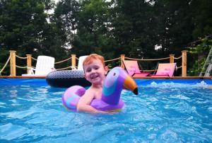 a young boy in a swimming pool with a rubber duck toy at Domek Rodzinny na Roztoczu in Nowiny