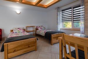 a room with two beds and a table and a window at Domek Rodzinny na Roztoczu in Nowiny +14 photos