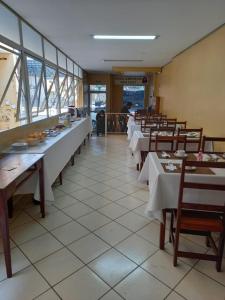 a dining room with tables and chairs and windows at Novo Hotel in Itajubá