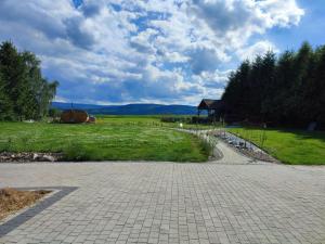 un camino de ladrillo que conduce a un campo con un edificio en Karkonosze, en Grudza