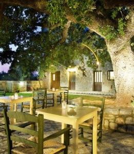 un grupo de mesas y sillas bajo un árbol en Vlyhada Guesthouse, en Pyrgos Dirou