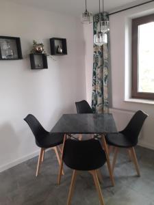 ein Esszimmer mit einem schwarzen Tisch und Stühlen in der Unterkunft Apartament Wiżajny in Wiżajny