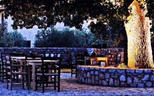 un parque con mesas y sillas y una pared de piedra en Vlyhada Guesthouse, en Pyrgos Dirou