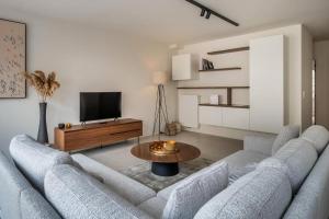 een woonkamer met twee banken en een tafel bij - Jacques-Annie - Fully renovated magnificent apt 50m from the beach in Koksijde