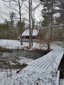 a red barn in the snow next to a river at Two Brooks Lodge in Bennington