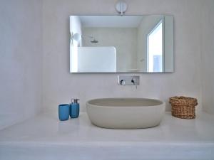 ein weißes Badezimmer mit einem Waschbecken und einem Spiegel in der Unterkunft Etherio Apartment III in Piso Livadi