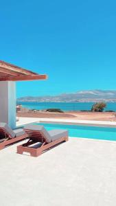 a pool with two lounge chairs and a view of the ocean at Voras Villa Panagia Beach in Antiparos