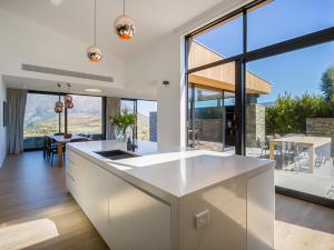 a kitchen with a white island and a large window at Point Vista - Queenstown Luxury in Queenstown
